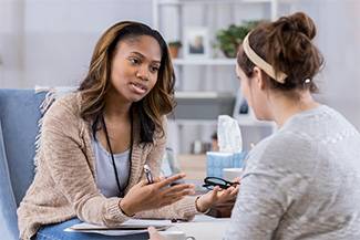 Two woman leaning in and talking with each other