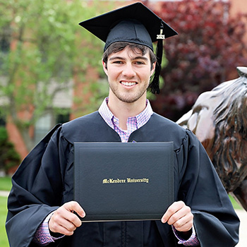 Online Student Holding Diploma at Commencement